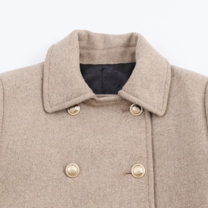 Detail of wool blend coat collar with textured fabric and golden embossed buttons