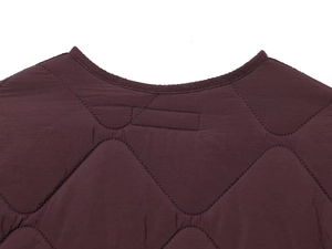 Detail of the diamond-quilted pattern and round neckline on a dark burgundy jacket
