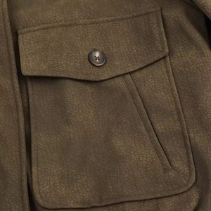 Vue macro d'une veste en suédine montrant une poche texturée à rabat et bouton