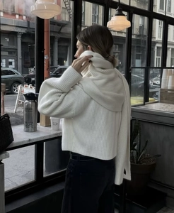 Detail of white ribbed knit sweater featuring a matching long scarf and chunky texture