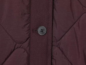 Macro shot of burgundy quilted jacket featuring wavy patterns and herringbone placket detail