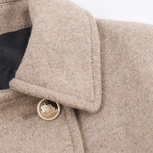 Close-up of a camel wool coat with classic lapel and premium vintage gold shield button
