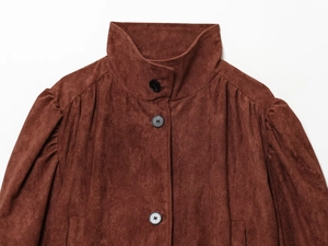 Detail of reddish brown suede jacket featuring high neck collar and ruched shoulder sleeve