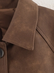 Detail of brown faux suede jacket collar with black button and fine stitching texture