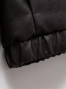 Détail du poignet d'une veste en similicuir noir avec ourlet élastique et texture grainée