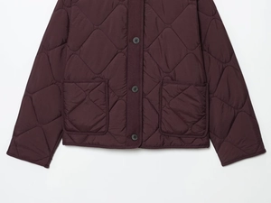 Detail of diamond quilted texture and large front pockets on a burgundy jacket