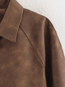 Detailed close-up of brown suede PU jacket featuring lapel collar and raglan sleeve stitching