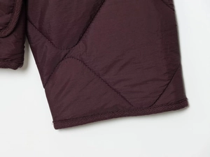Detailed close-up of dark purple quilted jacket fabric with premium diamond stitching