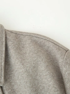 Detailed close-up of shoulder stitching and soft wool blend texture on the beige coat