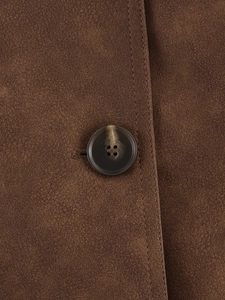Detailed macro view of amber texture button on dark brown faux suede jacket with stitching
