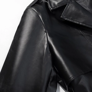 Detail of black faux leather trench coat with notched lapels and shoulder epaulettes