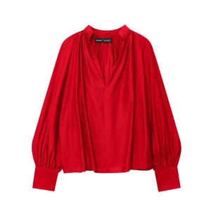 Detail of red V-neck blouse showing silk-like fabric texture and pleated shoulders