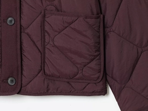 Macro detail of wine red quilted jacket featuring diamond patterns and large patch pocket