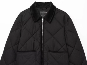 Détail d'une veste matelassée noire avec col en velours côtelé et fermeture éclair