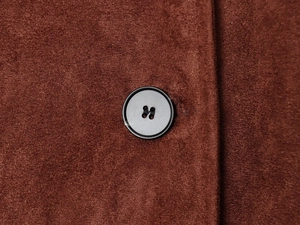 Macro shot of brown suede jacket texture with a black button and detailed stitching
