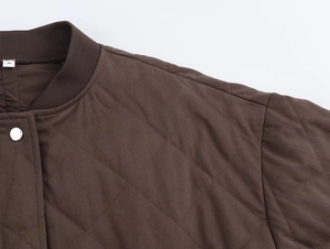 Detail of brown quilted jacket featuring a ribbed collar and silver metal button snap