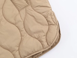 Vue détaillée de la veste matelassée kaki avec coutures ondulées et tissu ripstop