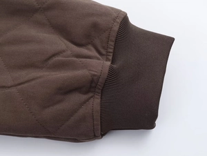 Detail of quilted bomber jacket showing ribbed cuffs and textured twill fabric