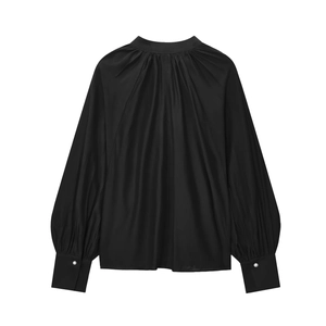 Detail of elegant black satin blouse featuring pleated high neck and pearl button cuffs