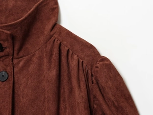 Detail of dark brown suede jacket with pleated shoulders and stand-up collar