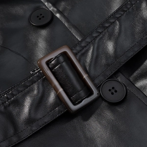 Detail of black faux leather trench coat showing tortoiseshell belt buckle and black buttons