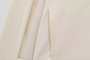 Detailansicht der feinen Nähte und beige Köperstoff-Textur einer modischen Bomberjacke