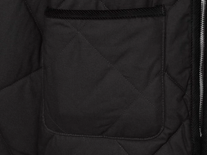 Détail d'une veste matelassée noire avec motif en losanges et fermeture éclair en métal