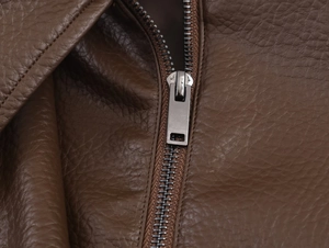 Dettaglio della cerniera in metallo su giacca in pelle PU marrone con texture