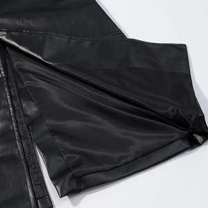 Detail view of the high side slit and smooth texture on a black faux leather trench coat