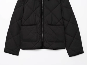 Détail d'une veste matelassée noire avec fermeture éclair et grandes poches plaquées