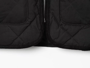 Détail de la veste matelassée noire avec fermeture éclair et bordure en velours côtelé