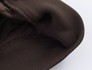 Detail of dark brown ribbed knit cuffs and hem on the quilted bomber jacket