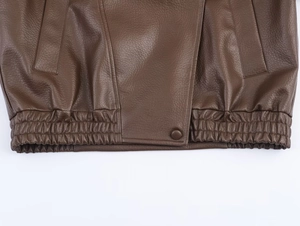 Détail d'une veste en cuir PU marron foncé avec ourlet élastique et finitions soignées