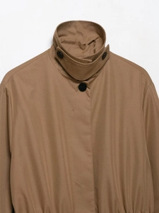 Close-up of khaki parka collar with adjustable windproof strap and black button detail