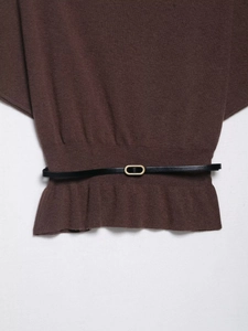 Close-up of brown knit fabric with vertical ribbing and slim black belt with gold buckle