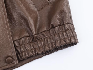 Détail de l'ourlet de veste en similicuir marron foncé avec taille élastique et bouton