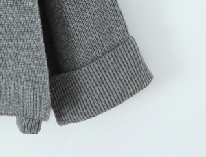 Macro view of grey rib-knit texture and elastic cuffs on a loose wool blend sweater