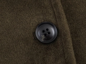 Macro shot of high-quality wool fabric texture and black resin button on dark olive jacket