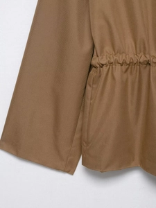 Detailed macro view of khaki parka jacket showing ribbed twill fabric and drawstring waist