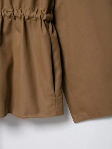 Detail of adjustable drawstring waist and side pocket on khaki parka jacket