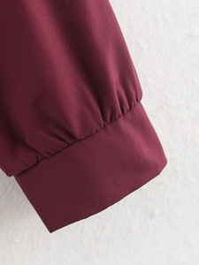 Détail de la veste bordeaux montrant le poignet froncé et la texture tissée lisse