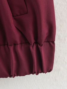 Vue macro du tissu rouge foncé avec poignet élastiqué froncé sur la manche de veste