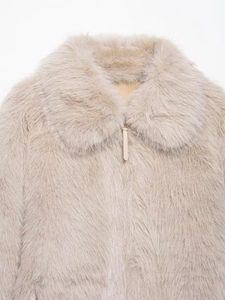 Close-up of cream faux fur jacket featuring a round neck and leather zipper pull detail