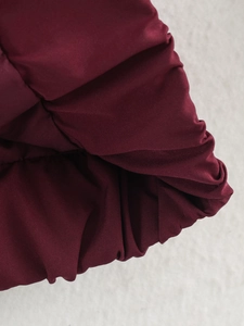 Détail macro du tissu coupe-vent bordeaux de la veste avec texture d'ourlet froncé
