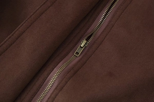 Close-up of brown suede jacket texture with premium metal zipper and neat stitching