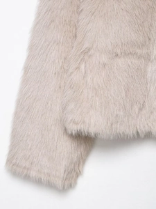 Detailed view of plush faux fur texture on sleeve and hem of beige cropped jacket