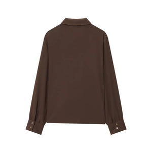 Détail des manches de chemise marron foncé avec boutons dorés et texture fluide