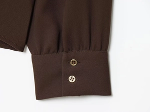 Détail des manches de chemise en crêpe marron avec d'élégants boutons dorés
