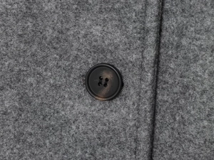 Close-up of grey wool fabric texture and marble pattern button on the stylish coat