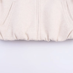 Detailed close-up of beige bomber jacket hem with elastic waist and side pockets